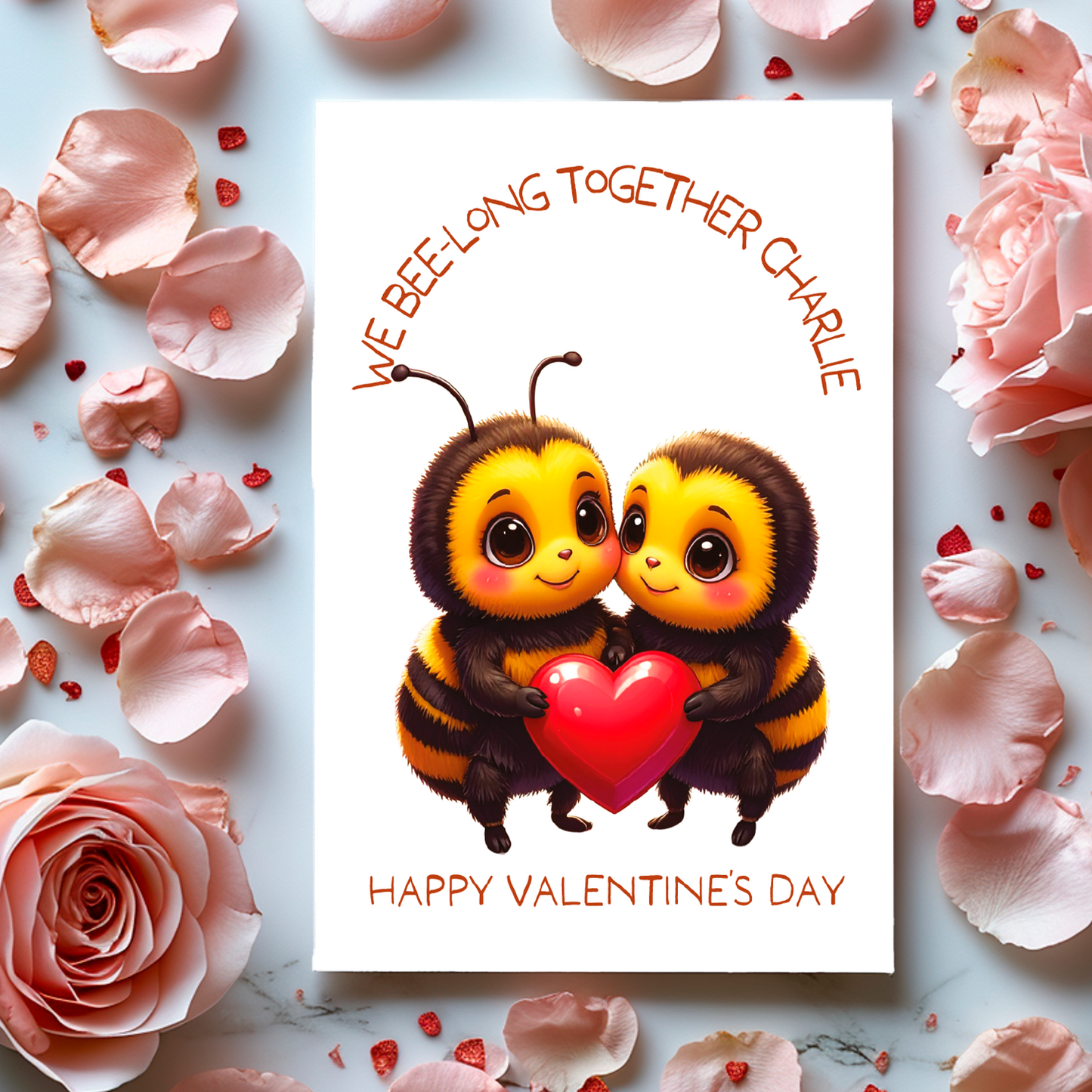 Valentine's Day card with two bees holding a heart and the text 'We bee-long together' and Happy valentines Day' surrounded by flowers and petals.