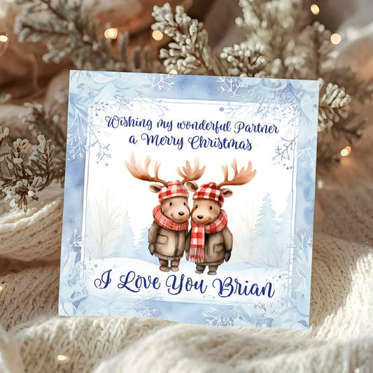 Christmas card with two deer wearing hats and scarves, set against a snowy background.