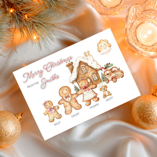Christmas card with gingerbread family design surrounded by festive decorations on a soft fabric background.