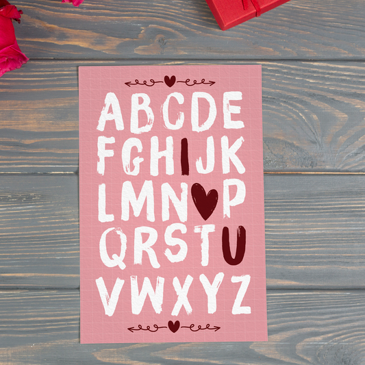 Pink alphabet poster with white and red letters on a wooden surface