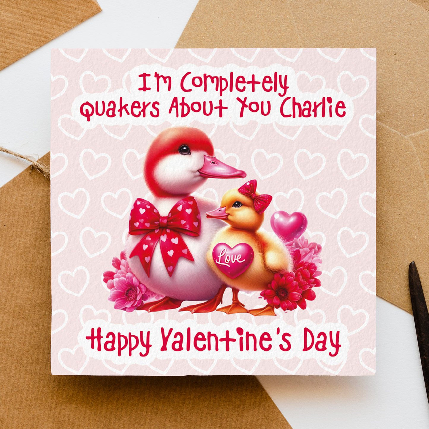 Valentine's Day card with two ducks and heart designs on a pink background