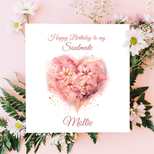 Greeting card with floral heart design and 'Happy Birthday to my Soulmate Mollie' text, surrounded by flowers and leaves on a pink background.