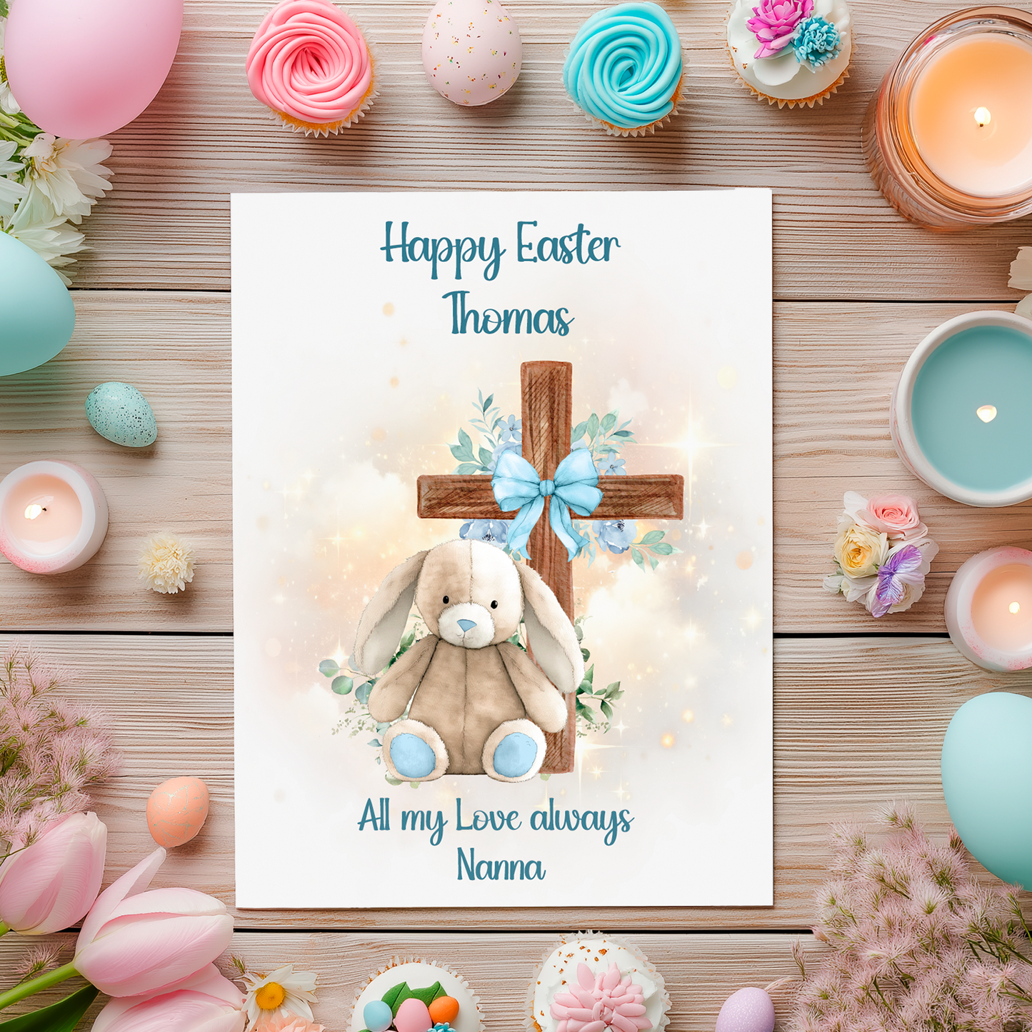 Easter card with a blue bunny and cross surrounded by Easter decorations on a wooden surface.Can be personalised with name and relation